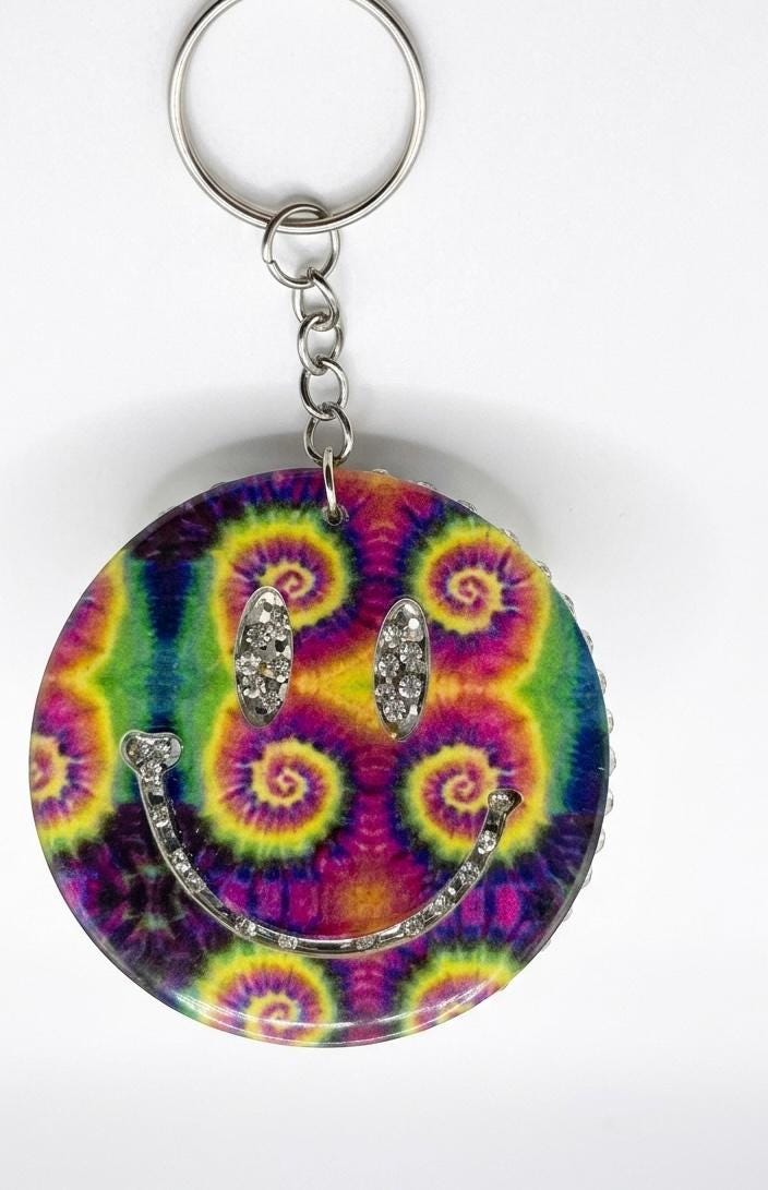 Tie-dye keychain with smiley face design and rhinestones on a white background